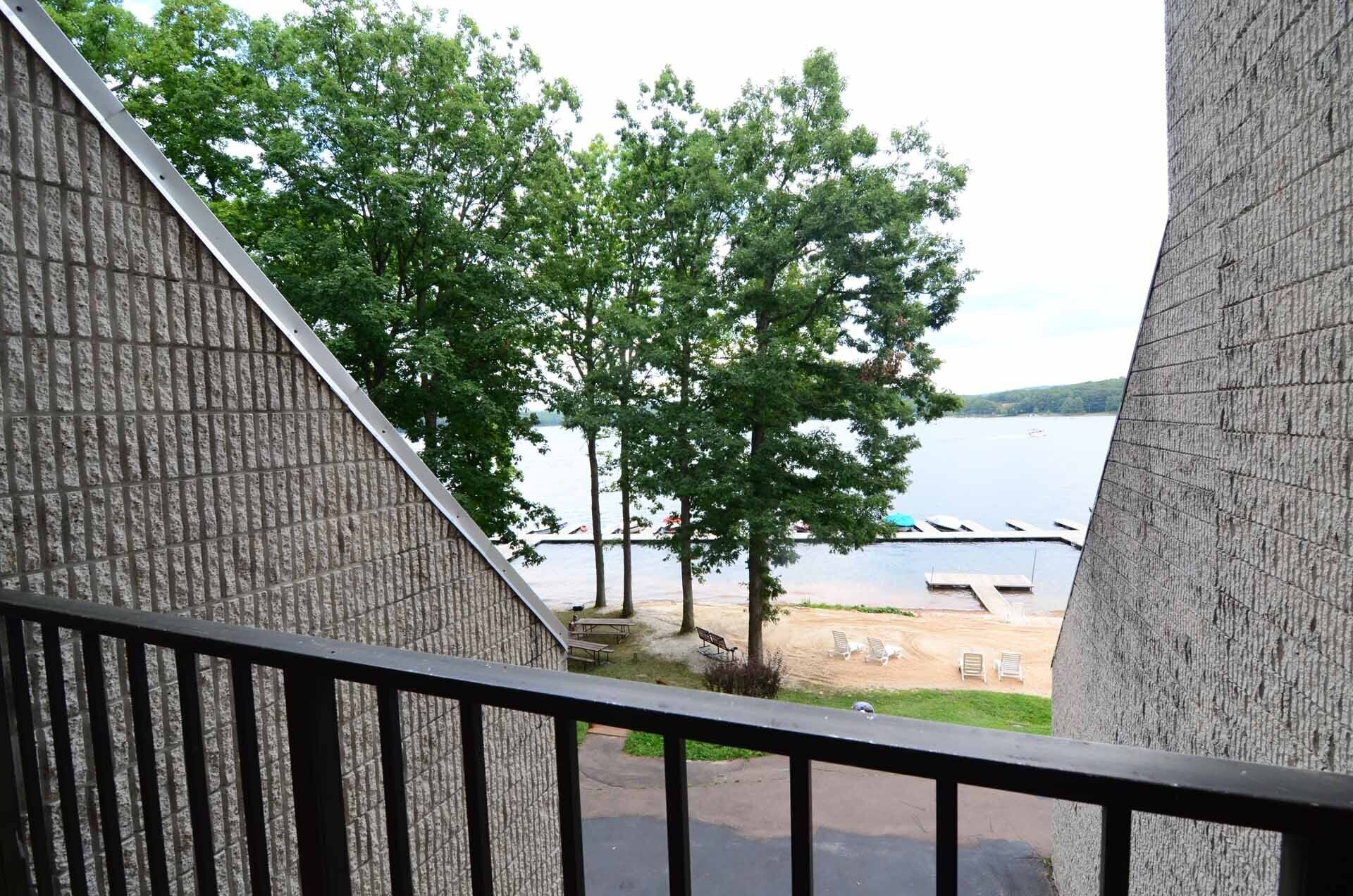 A view from a balcony overlooking a lake with trees and docked boats.