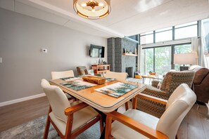 Una sala de estar moderna con una mesa de comedor, sillas, un sofá, un televisor y una chimenea.