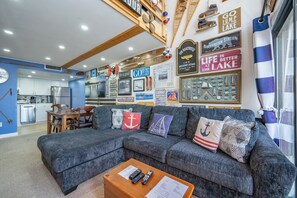 A living room with a sofa, coffee table, and a kitchen in the background.