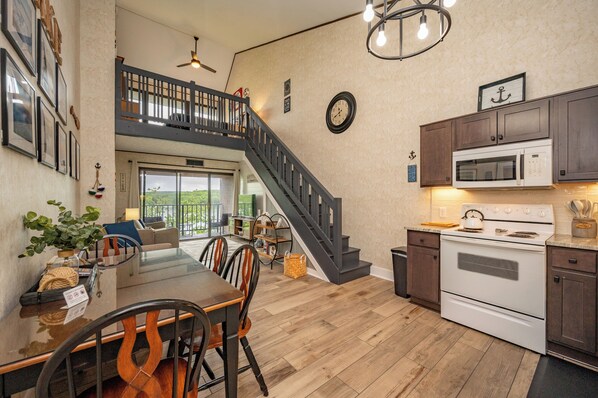 A spacious kitchen with a dining area, a staircase, and a view to the outside.