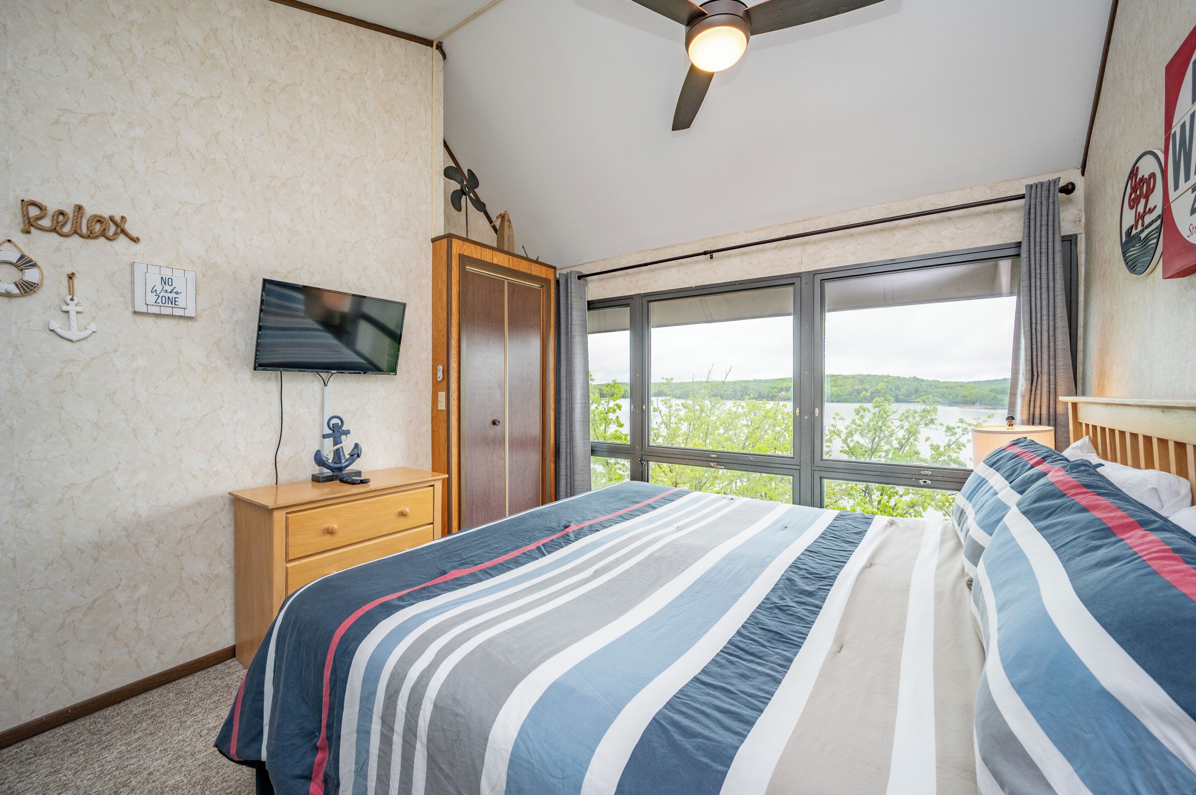 A bedroom with a bed, a TV, a wardrobe, and a window with a view.