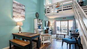 A room with a dining table, bench, sofa, and a staircase. - Will O' The Wisp: 710H Studio Loft/One Bath (Oakland)