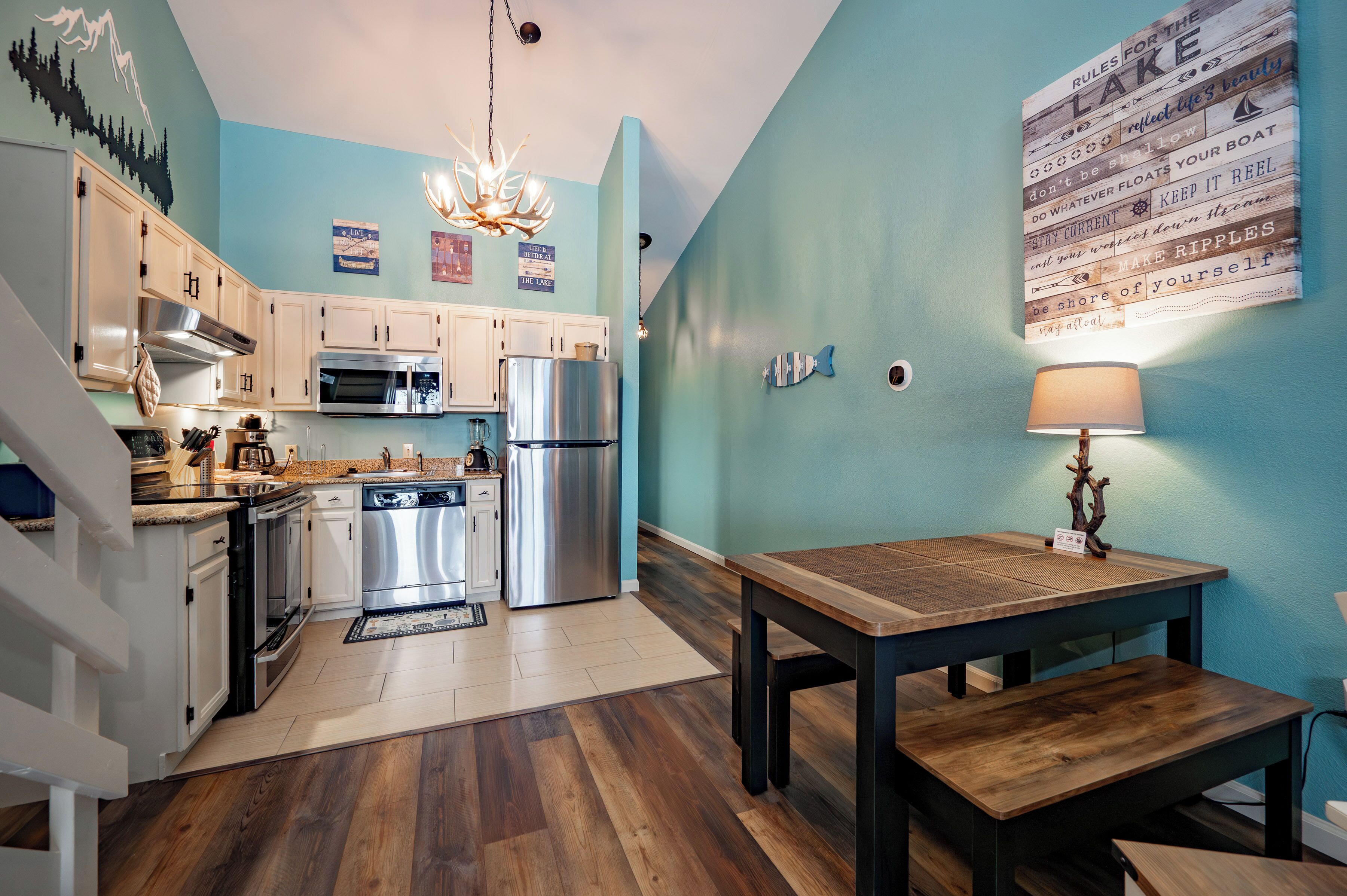 Une cuisine moderne dotée d’appareils électroménagers en acier inoxydable, de planchers en bois et d’un mur d’accent de couleur turquoise.