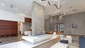 Eine moderne Lobby mit Sitzgelegenheit, einer Rezeption und einer Wand mit geometrischen Mustern.
