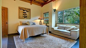 Une chambre à coucher avec un lit, un canapé, une grande fenêtre et un plafond en bois.