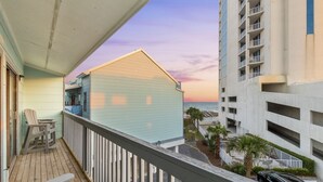 A balcony with a view of the ocean and a building with balconies. - 🏖️ Beachfront Family Fun – Pool, Switch & Karaoke (Gulf Shores)