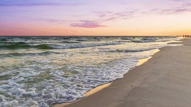 A beach with waves at the shore and a sunset in the background. - 🏖️ Beachfront Family Fun – Pool, Switch & Karaoke (Gulf Shores)