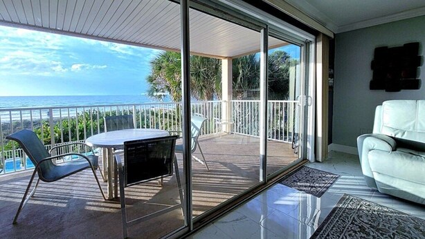 Ein Balkon mit Blick auf das Meer, ein weißes Sofa und ein Tisch mit Stühlen.