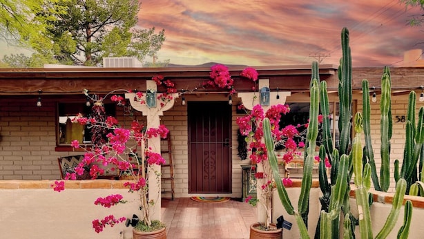 A house with a brick exterior, a wooden pergola with pink bougainvillea, and tall cacti. - Little Gem - Thoughtfully Curated Desert Escape (Tucson)