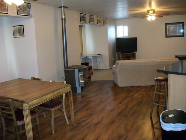 A living room with a wooden dining table, a sofa, a TV, and a ceiling fan.