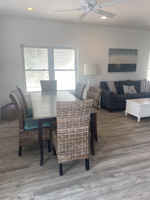 A dining area with a table and chairs, a sofa, a lamp, and a ceiling fan.