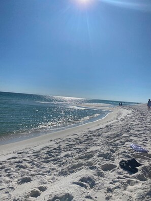 A sandy beach with footprints and a black shoe on the sand. - BEACH HOUSE including 100 DOLLAR GC with a 4 day or more STAY. (Pensacola Beach)
