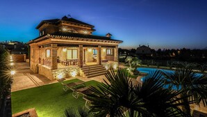 A two-story house with a swimming pool, a well-lit patio, and a clear view of the surrounding area.