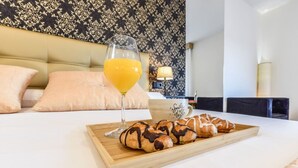 A neatly made bed with a tray of croissants and a glass of orange juice.