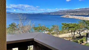 A coastal view with a clear sky, a rocky shoreline, and sparse vegetation. - Holiday apartment comfortably furnished just 20 m from the sea (Šilo)