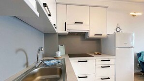 A compact kitchen with a stainless steel sink, white cabinets, a built-in oven, and a small countertop. - Holiday apartment comfortably furnished just 20 m from the sea (Šilo)