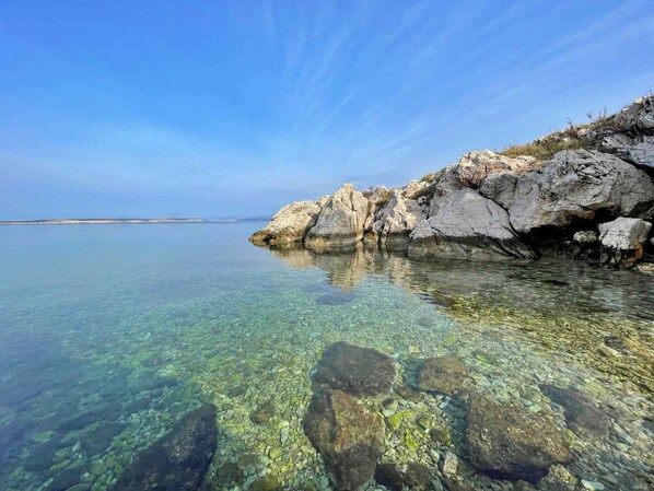 A clear coastal view with rocky formations and calm waters.