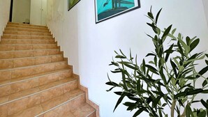 Eine Treppe führt zu einem Raum mit weißen Wänden und gerahmten Bildern.