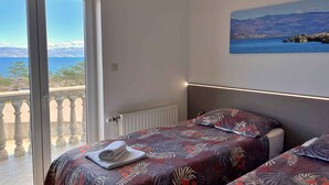 Ein Schlafzimmer mit einem Bett, einem Fenster und einem Gemälde einer Küstenlandschaft.