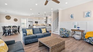A modern living room with a sofa, coffee table, and patterned armchair. - Modern Luxury Home w/ Private Pool - Cherry Grove Beach (North Myrtle Beach)