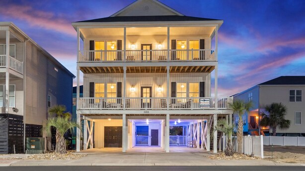 A two-story building with a balcony on the second floor, a covered entryway, and a sign indicating a business. - Modern Luxury Home w/ Private Pool - Cherry Grove Beach (North Myrtle Beach)
