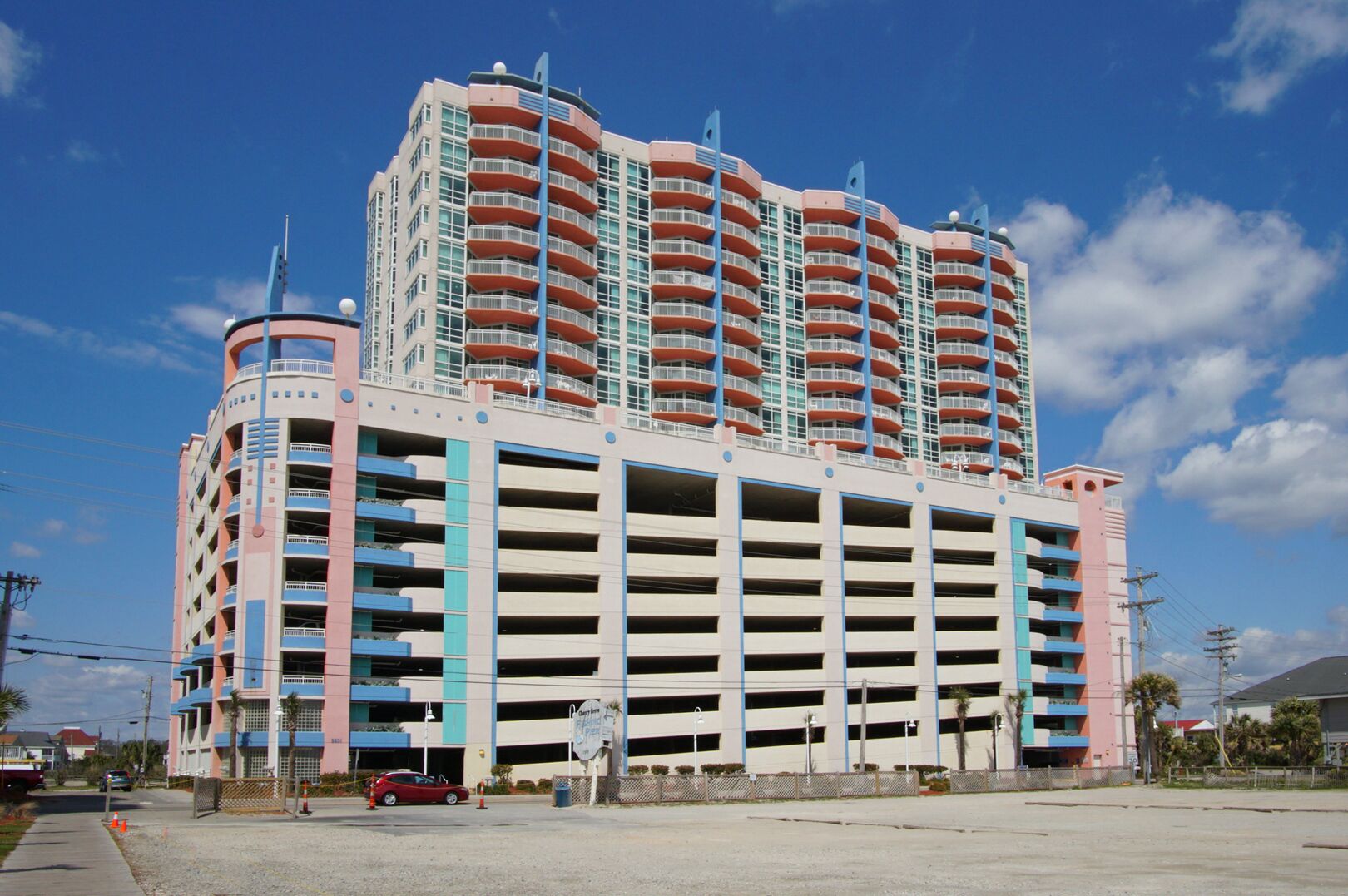 A multi-story parking garage with a central atrium and a red car parked in front.