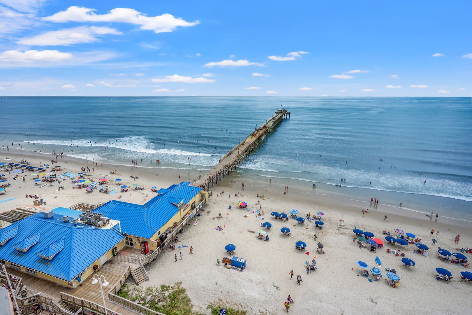 Ein Strand mit einer Seebrücke, Sonnenschirmen und Liegestühlen.