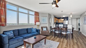 A spacious living area with a blue sofa, wooden dining table, and chairs.
