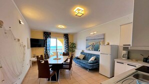 Un apartamento moderno con comedor, sofá, cocina y vista al mar.