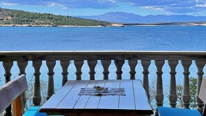 Una mesa de madera con un menú en un balcón con vista a un cuerpo de agua y montañas a lo lejos.