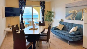 Un comedor con mesa y sillas, un sofá, una planta y vista al mar.