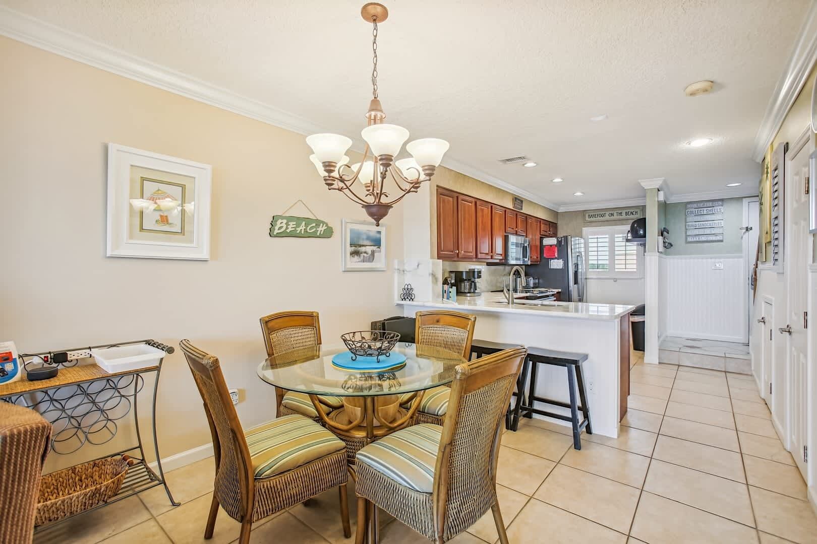 A dining area with wicker chairs and a glass table, a kitchen with wooden cabinets, and a sign reading "BEACH".