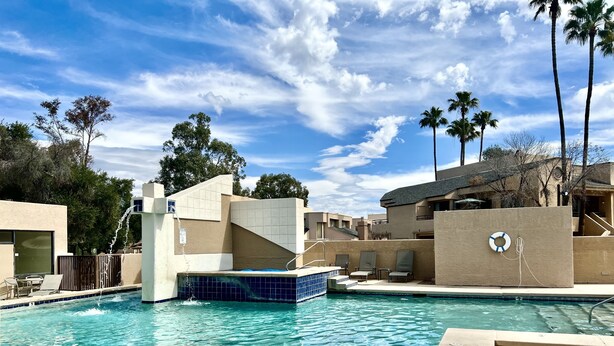 A swimming pool with a water feature, lounge chairs, and palm trees. - Contemporary Condo with Private Garden Patio and Pool Access (Tucson)