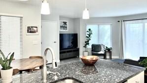 A modern kitchen with granite countertops, stainless steel appliances, and pendant lighting. - Contemporary Condo with Private Garden Patio and Pool Access (Tucson)