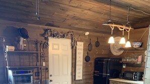 A cozy kitchen with wooden walls, a built-in oven, a refrigerator, and a dining area with chairs. - ❤️Dixieland Delight❤️Studio. Pet friendly WITH FEE 🐕🐈❤️❤️❤️❤️❤️ (New Port Richey)