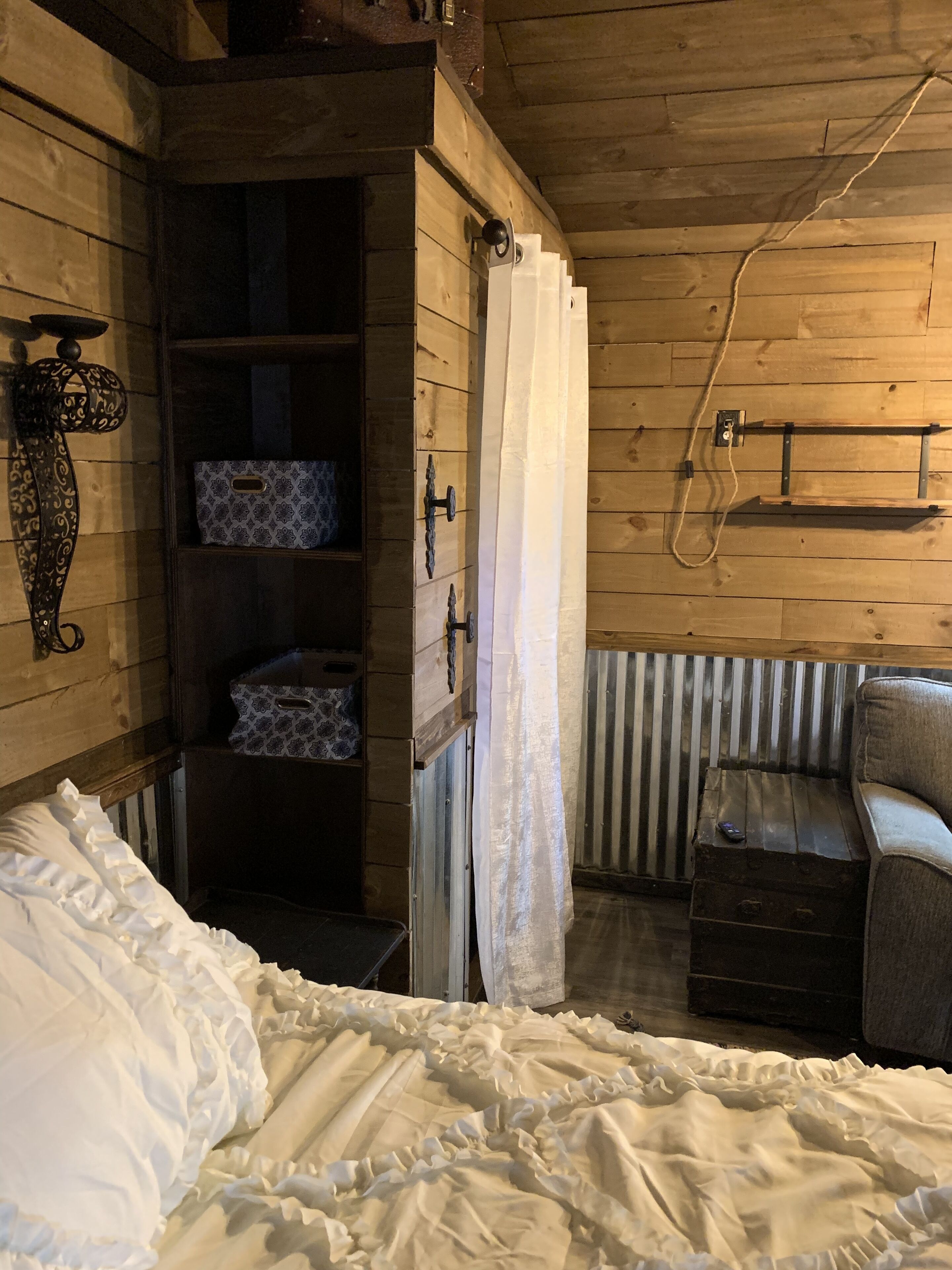 A cozy room with a bed, a wardrobe, a chair, and a small table.