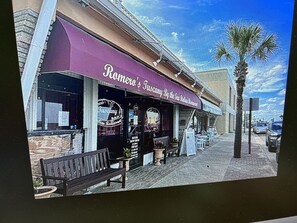A restaurant with a purple awning and outdoor seating.