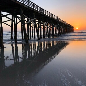 A pier extending into the water with a sunset in the background.