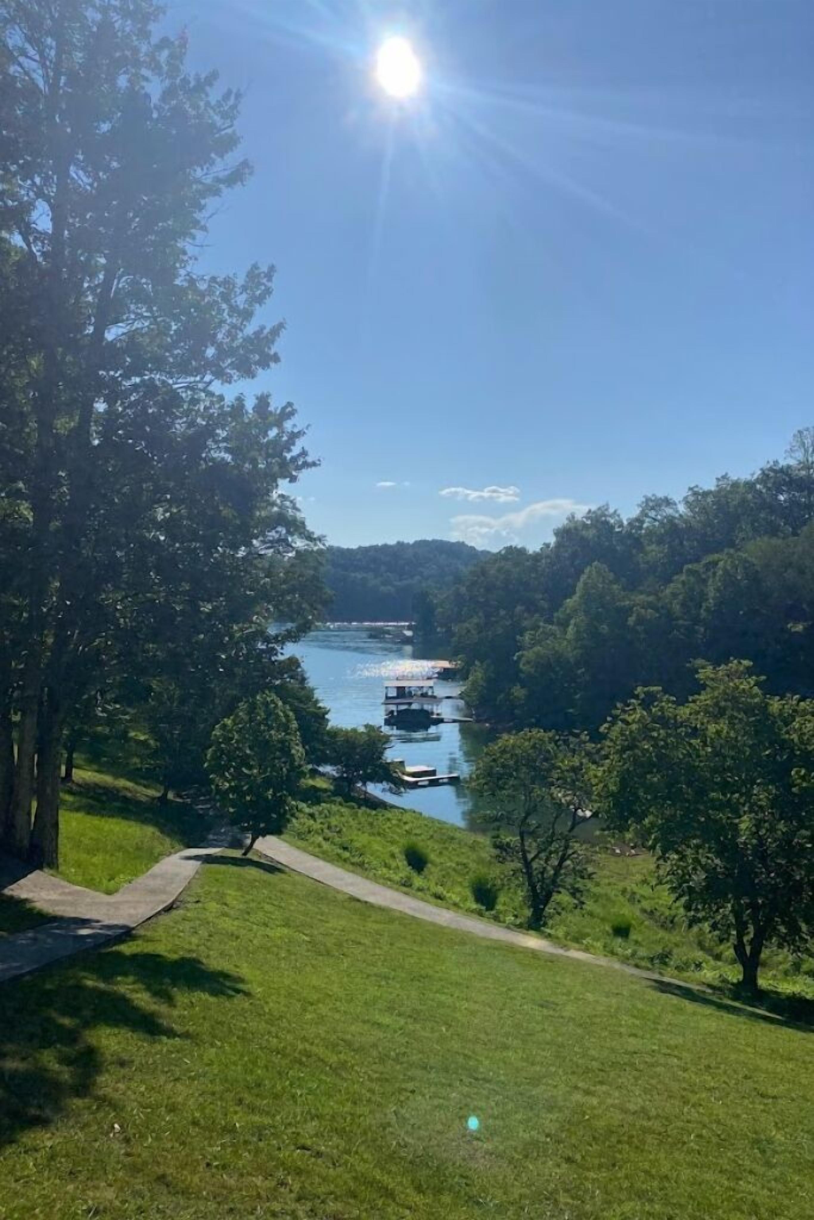 Vista sul fiume con barche, alberi e cielo sereno.