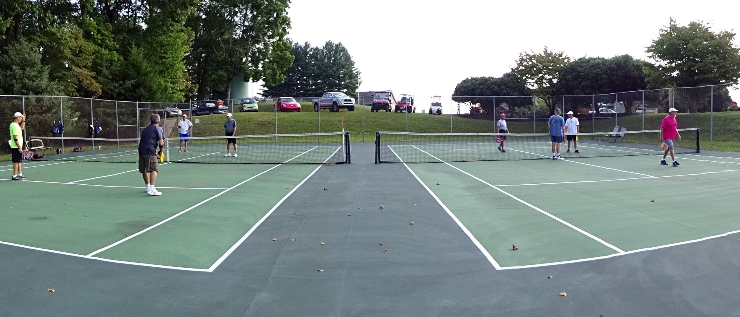 Un court de tennis avec des joueurs, un filet et une surface verte.