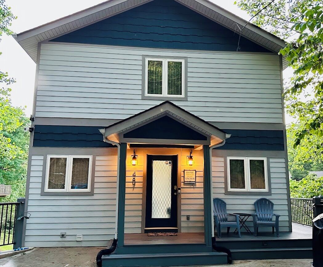 A two-story house with a porch, two windows on the upper floor, and a door with a sign that reads "Home Sweet Home."