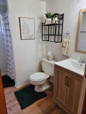 Ein Badezimmer mit Toilette, Waschbecken, einem Holzschrank und einem Handtuchhalter.