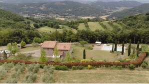 A rural landscape with a stone building, a swimming pool, and a fenced garden. - Villa Betta By MMega (Città di Castello)