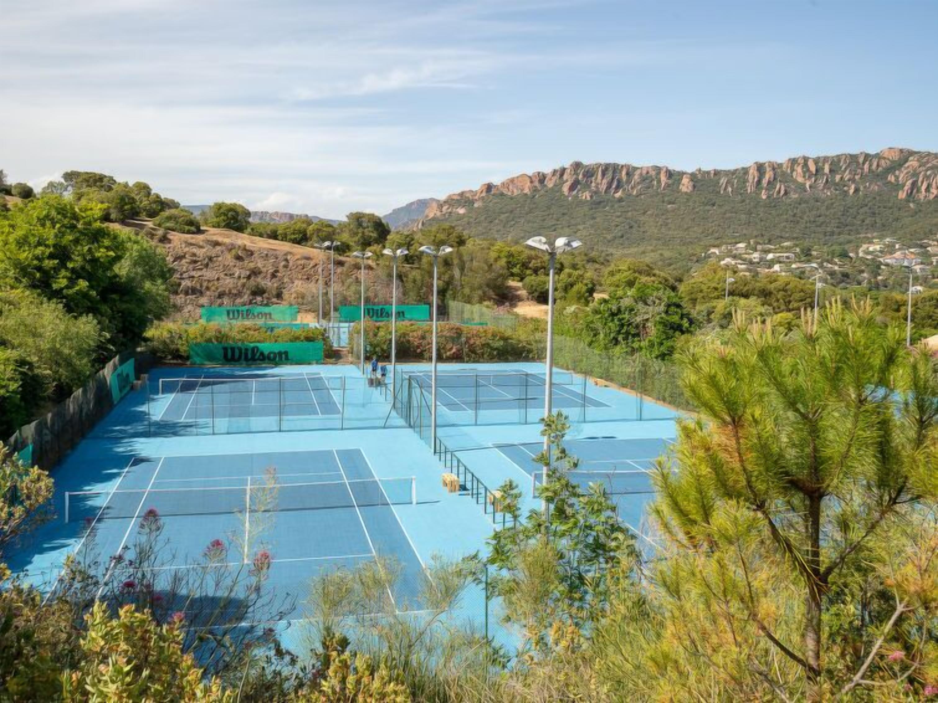 Una pista de tennis envoltada de vegetació i turons.