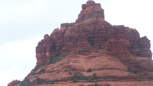 Une vaste formation rocheuse rouge, caractérisée par un sommet proéminent et une structure en couches.