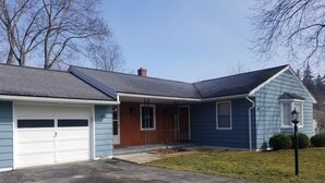 Une maison d’habitation avec un garage, un porche à l’avant et un petit jardin devant la maison.