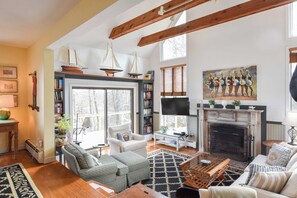 Una sala de estar amplia con chimenea, ventanas grandes y una estantería.