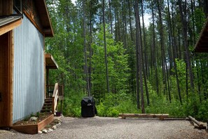 A wooden cabin with a metal exterior, surrounded by a forest.