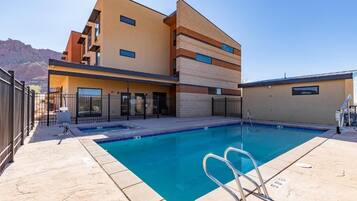 Een seizoensgebonden buitenzwembad, ligstoelen bij het zwembad