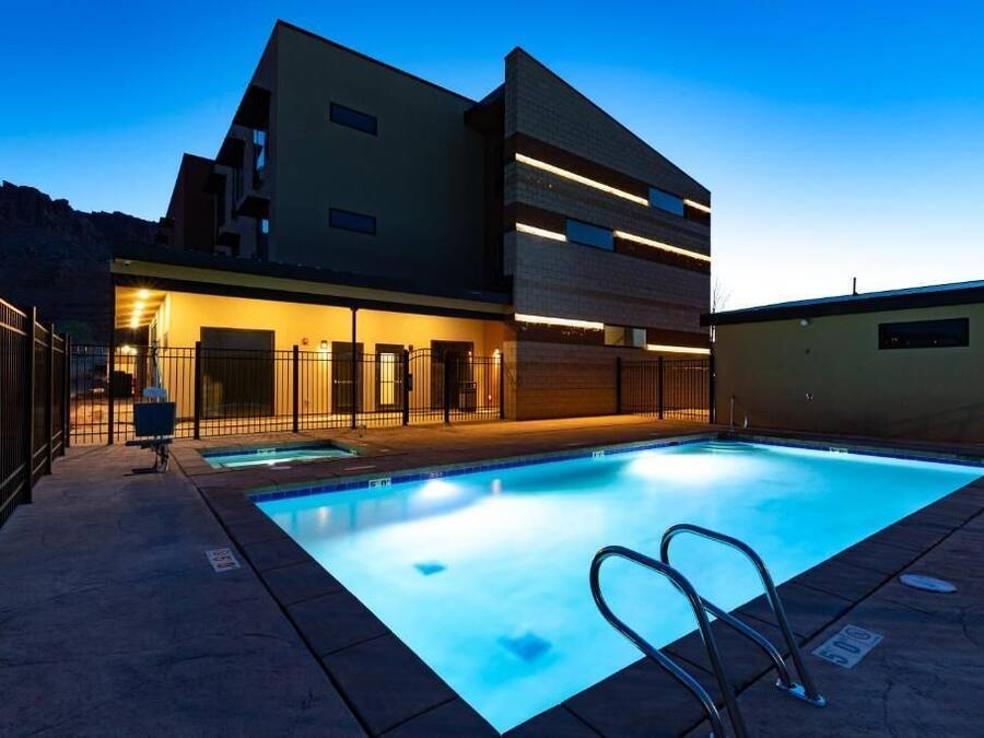 A modern building with a swimming pool, featuring a multi-level design and a well-lit exterior.